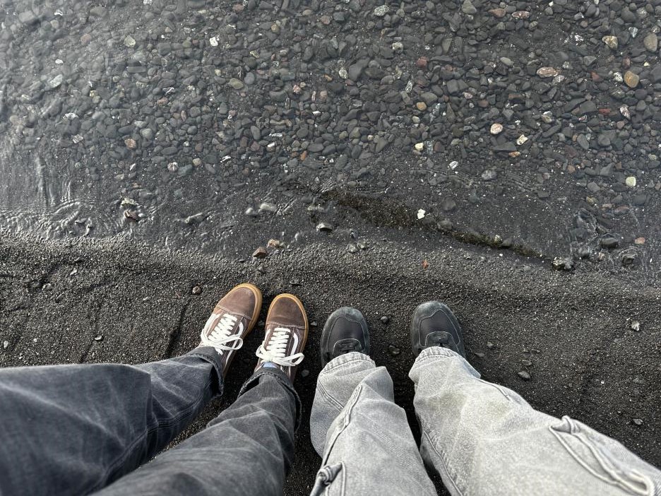 two pairs of shoes next to a lake shore